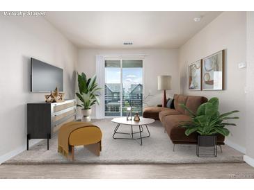 Cozy living room features a comfortable brown sofa and sliding doors to a balcony with neighborhood views at 4100 Albion St # 523, Denver, CO 80216