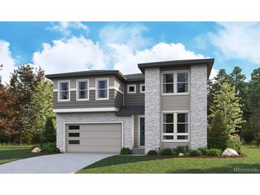Modern two-story home featuring stone accents, gray siding, a two-car garage, and a well-manicured front lawn at 8272 Snake River St, Littleton, CO 80125