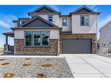 Beautiful two-story home featuring stone accents, gray siding, a two-car garage, and a concrete driveway at 5698 Farrier Pt, Castle Rock, CO 80104