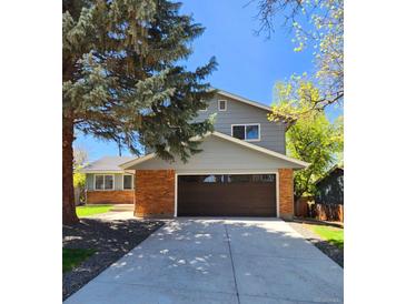 Inviting two-story home with a spacious driveway, brick accents, and an attached two-car garage at 6521 Zinnia St, Arvada, CO 80004