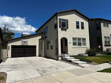 Charming two-story home featuring an attached garage, landscaped front yard and concrete driveway on a sunny day at 15547 W Vassar Ave, Lakewood, CO 80228