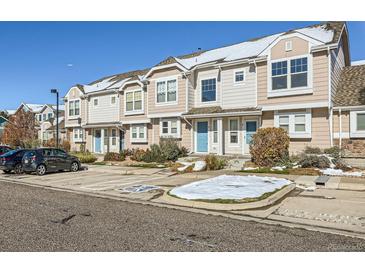 A row of tan townhomes with blue doors in a shared complex during the winter at 5888 Biscay St # D, Denver, CO 80249