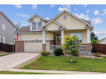 Charming two-story home featuring a welcoming porch, well-manicured lawn, and an attached two-car garage at 4293 Clover Ln, Brighton, CO 80601