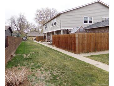 A spacious backyard features a lush green lawn and a tall wood fence, perfect for outdoor entertaining at 1015 Alta St, Longmont, CO 80501
