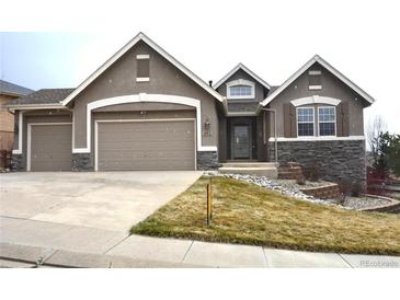 Inviting two-story home with stone accents, a well-manicured lawn, and a two-car garage, perfect for families at 461 Saber Creek Dr, Monument, CO 80132