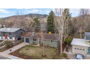 Charming exterior view of home with mature trees, blue accents, and mountain backdrop at 3545 Cloverleaf Dr, Boulder, CO 80304