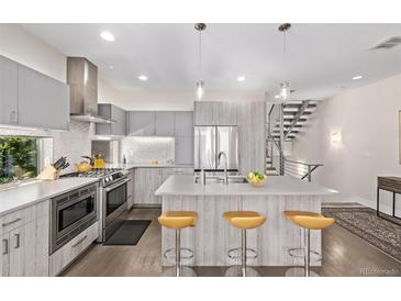 Modern kitchen with stainless steel appliances, island with seating, and gray cabinets at 1333 Elati St # 1, Denver, CO 80204
