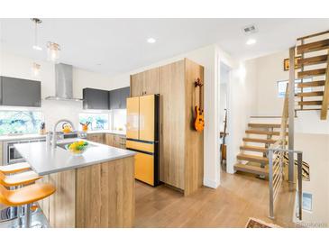 Bright kitchen featuring wooden cabinets, a kitchen island with seating, and a unique yellow refrigerator and stairs at 1333 Elati St # 1, Denver, CO 80204