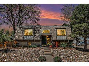 Inviting home featuring a unique roofline, stone landscaping, and a serene, tree-lined setting at 9349 E Chenango Ave, Greenwood Village, CO 80111