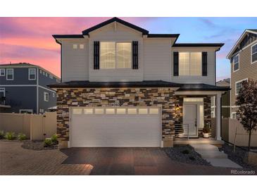 Charming two-story home featuring stone accents, white siding, and a two-car garage during a colorful dusk at 4060 N Rome St, Aurora, CO 80019