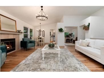 Bright living room featuring hardwood floors, a fireplace, modern furnishings, and an open floor plan at 8543 Redstone St, Highlands Ranch, CO 80126