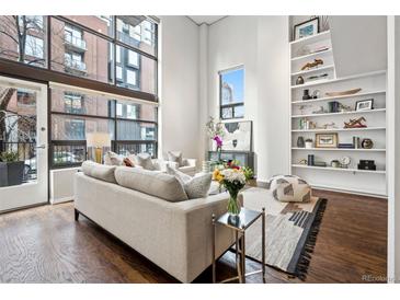 Bright living room featuring hardwood floors, large windows, and custom built-in shelving at 930 Acoma St # 108, Denver, CO 80204