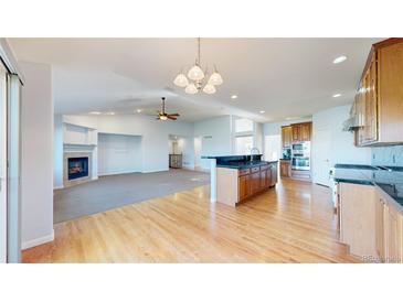 Spacious living room featuring a fireplace, hardwood floors, and an open layout to the kitchen at 14701 Yosemite St, Brighton, CO 80602
