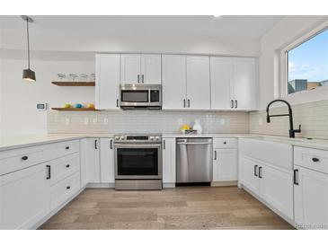 Modern kitchen featuring white cabinets, stainless steel appliances, and a stylish faucet at 1907 W Elk Pl, Denver, CO 80211