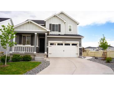 Charming two-story home featuring a covered porch, manicured lawn, and a two-car garage at 27655 E Geddes Pl, Aurora, CO 80016
