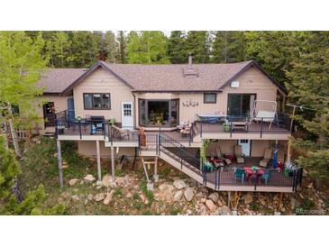 Charming home featuring a spacious deck with outdoor seating, perfect for enjoying the surrounding natural beauty at 11094 Thomas Dr, Conifer, CO 80433