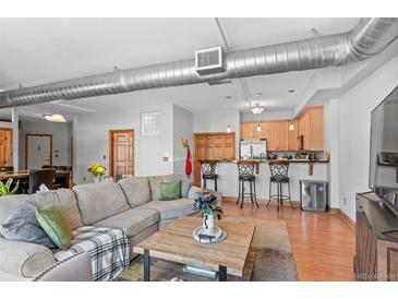 Open living space with a large sectional sofa, wood floors, and a kitchen with counter seating at 3299 Lowell Blvd # 102, Denver, CO 80211