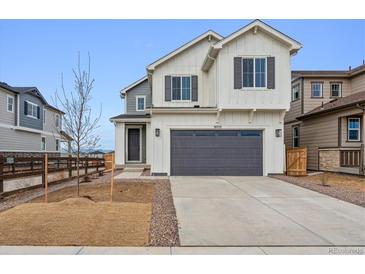 Two-story home featuring white siding, a gray garage door, and a well-manicured lawn at 9257 Truckee Ct, Commerce City, CO 80022
