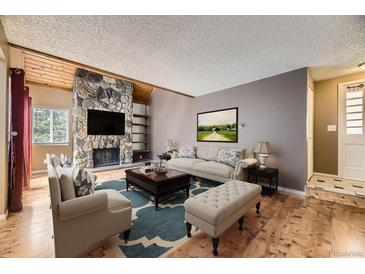 Inviting living room features a stone fireplace, hardwood floors, and contemporary furniture at 2694 S Xanadu Way # D, Aurora, CO 80014