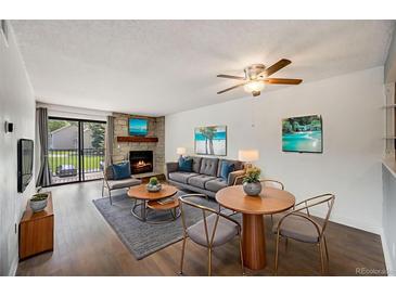 Inviting living room features a stone fireplace, hardwood floors and access to a balcony with outdoor views at 401 S Kalispell Way # 206, Aurora, CO 80017