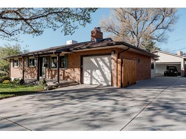 Brick home exterior featuring a garage, driveway, and manicured lawn, creating a welcoming curb appeal at 1475 S Urban Way, Lakewood, CO 80228