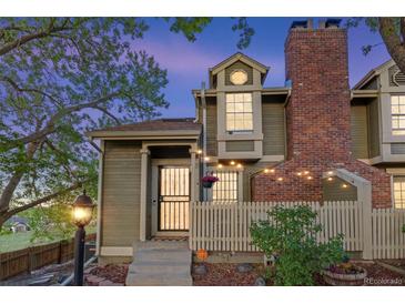 Charming two-story home boasts a brick chimney and cozy string lights enhancing the entryway's appeal at 1907 S Helena St # G, Aurora, CO 80013