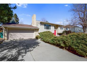 Charming two-story home featuring a red front door and a well-maintained front yard with mature bushes at 14453 W 3Rd Ave, Golden, CO 80401