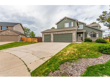 Two-story home boasts a three-car garage, green siding and a stone-accented facade, all under a cloudy sky at 21396 E Prentice Ln, Centennial, CO 80015