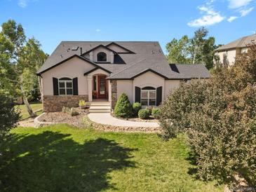 Charming single Gathering home features beautiful landscaping, stone accents, and a welcoming red front door at 5421 Potentilla Ct, Parker, CO 80134