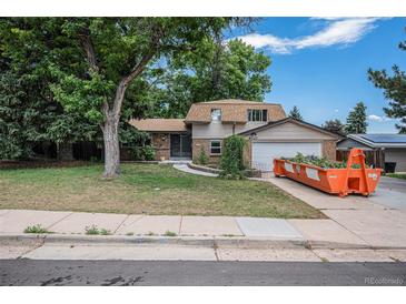 Traditional two-story home featuring a lush lawn, mature trees, and a charming blend of stone and siding exterior at 8727 E Girard Ave, Denver, CO 80231