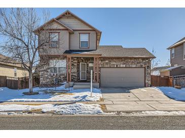 Two-story house with stone accents and attached garage, snow-covered front yard at 164 Bristlecone St, Brighton, CO 80601