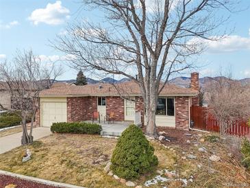 Brick ranch home with attached garage, landscaping, and mountain views at 4611 S Queen St, Littleton, CO 80127