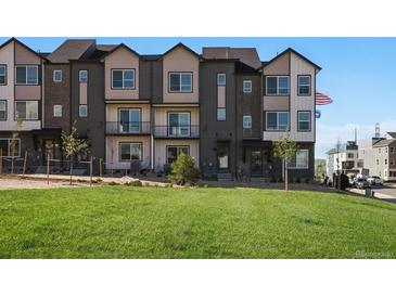 View of a modern townhome community with a well-maintained lawn and neutral color scheme at 14536 Mellow Ct, Morrison, CO 80465