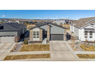 Beautiful single Gathering home featuring stone accents, manicured landscaping, and a two-car garage at 6759 Canyonpoint Rd, Castle Pines, CO 80108