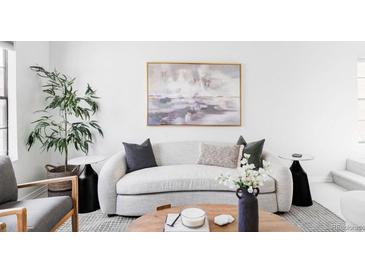 Bright living room features a neutral sofa, modern art, and a tall plant next to a window at 8787 Yukon St, Arvada, CO 80005
