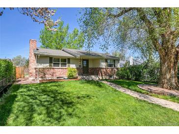 Charming single-story home featuring a brick facade, lush green lawn, and mature trees providing shade at 4781 S Grant St, Englewood, CO 80113