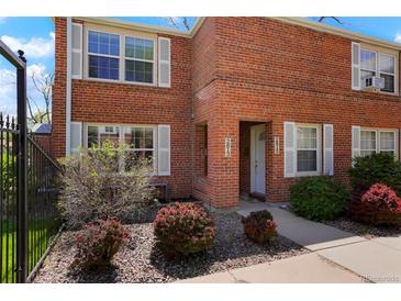 Charming brick townhouse with manicured landscaping, and a walkway to the front door at 2813 Jasmine St, Denver, CO 80207