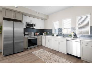 Modern kitchen featuring stainless steel appliances, subway tile backsplash, and hardwood floors at 2620 S Delaware St # 3, Denver, CO 80223