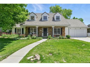 Charming stone-clad home featuring a lush green lawn and well-manicured flowerbeds at 3884 S Niagara Way, Denver, CO 80237
