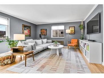 Bright living room features a comfortable gray sofa, unique décor, large window and hardwood floors at 85 N Ogden St # 13, Denver, CO 80218