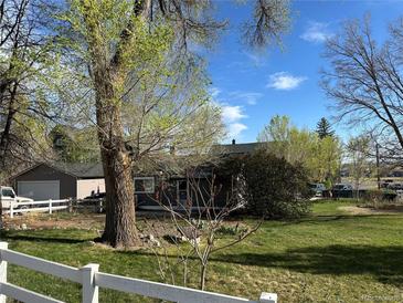Charming home with large mature trees, fenced yard, and lush green grass at 1129 2Nd Ave, Longmont, CO 80501