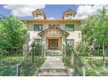 Brick two-story house with a classic design, landscaped yard, and a metal fence at 1827 N Bellaire St, Denver, CO 80220