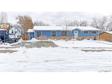 Charming blue single-story home featuring a spacious driveway covered in snow during the winter season at 7966 Ingalls St, Arvada, CO 80003