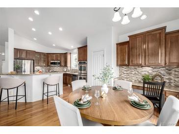 Bright dining area with a round wooden table, seating for six, and views of the gourmet kitchen at 8802 E 148Th Ln, Thornton, CO 80602