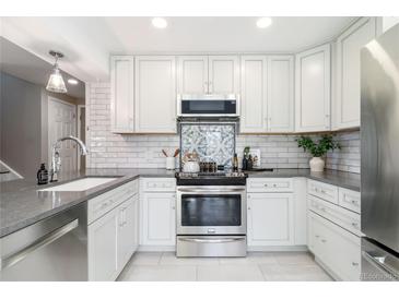 Well-lit kitchen with stainless steel appliances, undermount sink, gray countertops and white cabinets at 2645 S Xanadu Way # D, Aurora, CO 80014