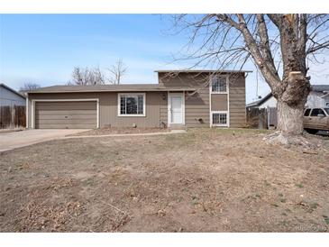 Split level home with a 2-car garage and muted brown siding under a blue sky at 15650 E Eldorado Dr, Aurora, CO 80013