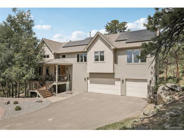 Beautiful two-story home with a three car garage, covered front porch, and solar panels on the roof at 30206 Telluride Ln, Evergreen, CO 80439