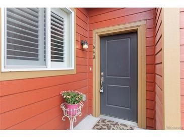 Charming entryway featuring a gray front door, red siding, and a delightful flower arrangement at 1640 Aspen Meadows Cir, Federal Heights, CO 80260