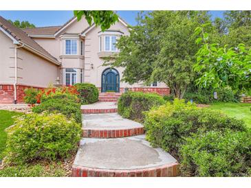 Beautiful two-story home featuring a manicured lawn and garden, brick accents, and a private entrance at 7355 Nile St, Arvada, CO 80007