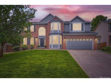 Beautiful two-story home with brick and siding, a well-manicured lawn, and an attached two-car garage at 9458 S Hackberry Ln, Highlands Ranch, CO 80129